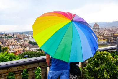 Two people look florence, they have a large rainbow umbrella 