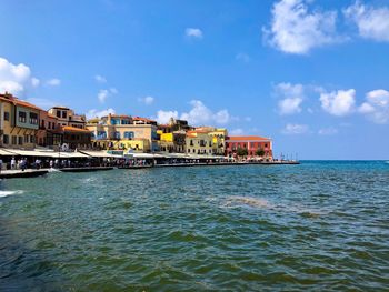 Buildings by sea against sky