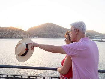 Relaxed senior couple watching the sea and giving directions to their