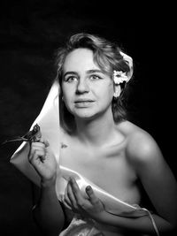 Thoughtful female model holding flower over black background