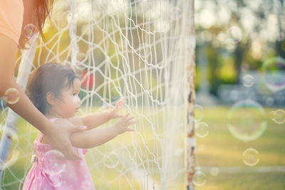 Mother with playful daughter on field