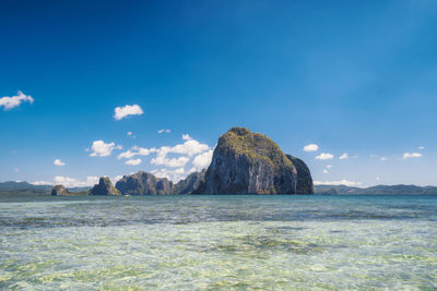 Scenic view of rocks in sea against blue sky