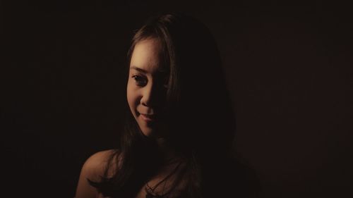 Portrait of young woman against black background