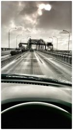 Road passing through highway against cloudy sky
