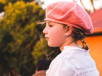 Close-up of thoughtful girl wearing flat cap against trees