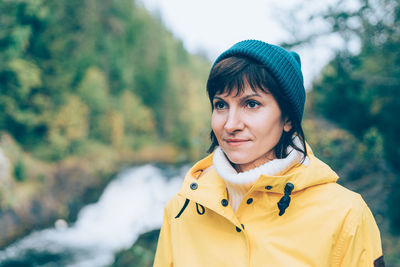 One with nature. back view of unrecognizable woman looking to forest and waterfall