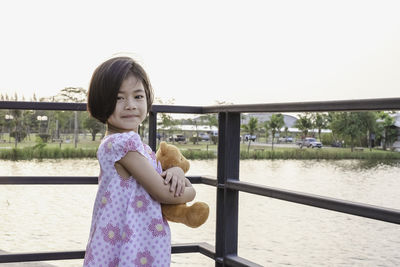 Portrait of a girl standing by water against clear sky