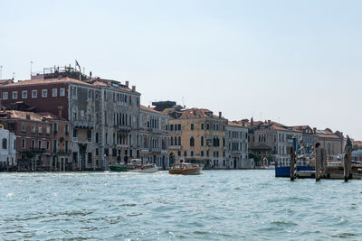 Buildings by sea against clear sky