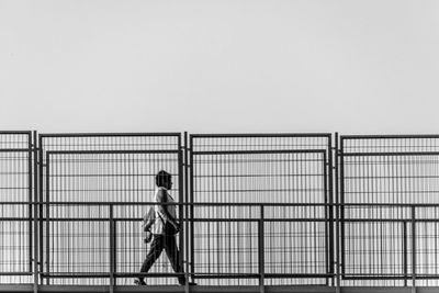 Side view of woman standing against railing against clear sky