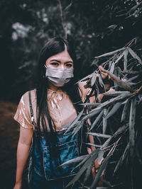 Portrait of young woman standing on field in forest