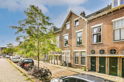 Cars on street by building against sky