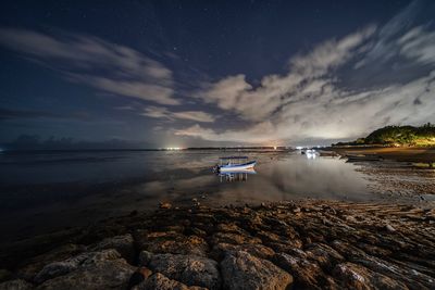 Boat on seashore against sky at night