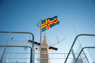 Low angle view of flags against clear blue sky