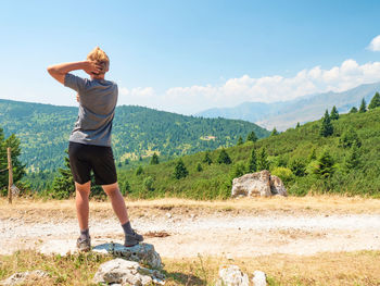 Blond hair teenager is dancing for fun on gravel road to alps hill peak. enjoy trek and funny moment