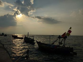 Fishing boats on sea against sky during sunset