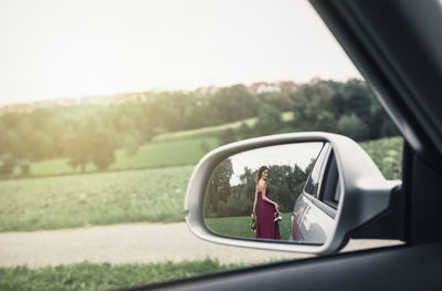 Reflection of man on side-view mirror of car