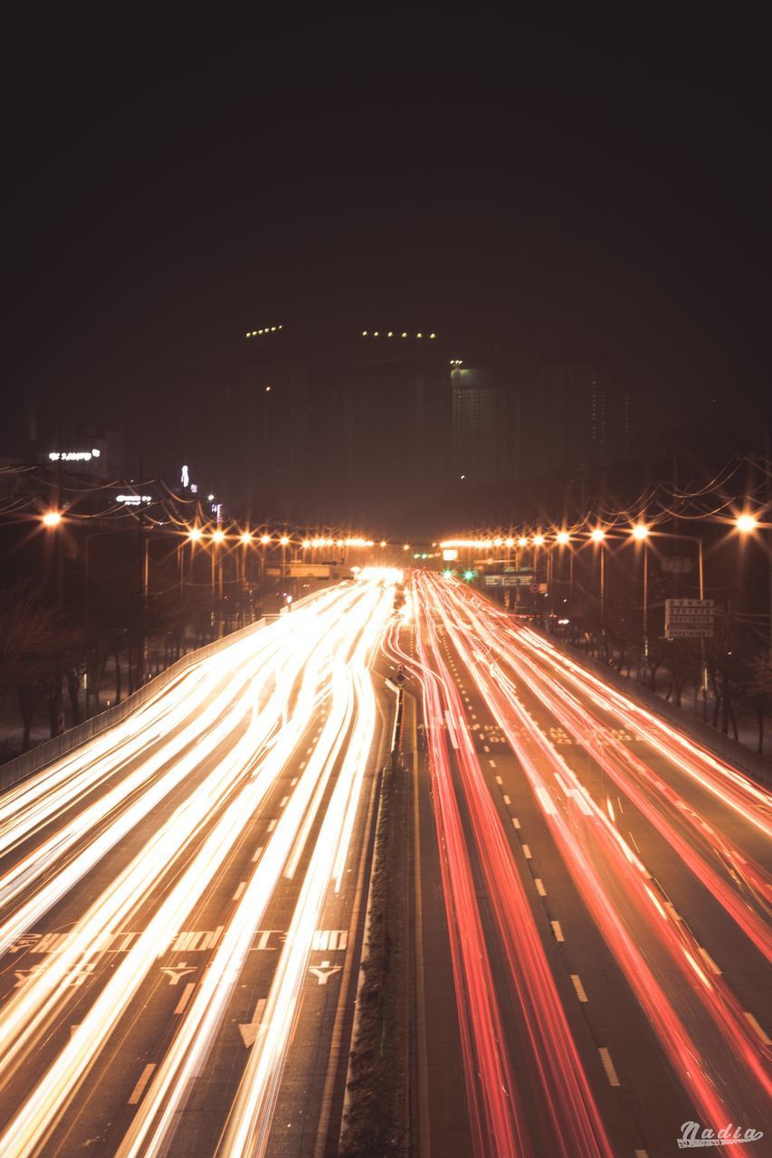 ILLUMINATED LIGHT TRAILS ON HIGHWAY AT NIGHT