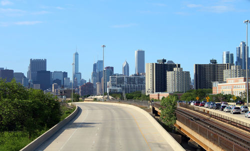 Road amidst buildings in city against sky