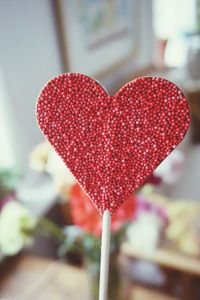 Close-up of red heart shape candy against wall