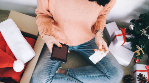 Midsection of woman holding credit card while using phone