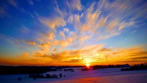 Scenic view of snowy field against sky during sunset