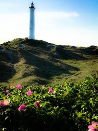 Scenic view of lighthouse by street amidst buildings against sky