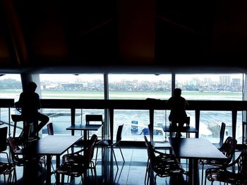 Rear view of silhouette people on table by sea