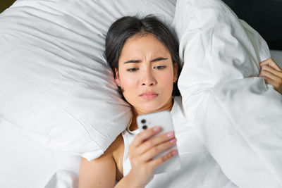 Portrait of young woman lying on bed at home