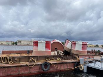 Boat moored at shore against cloudy sky