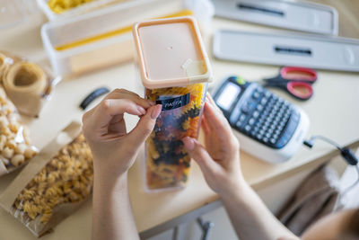 Cropped hand of woman labeling pasta container