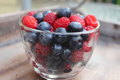 Close-up of blueberries and raspberries in glass bowl on table