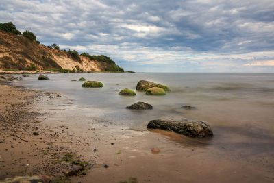 Scenic view of rocks on beach against sky