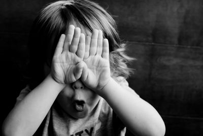 Close-up of boy covering eyes with hands
