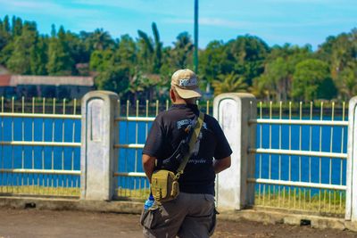 Full length of man standing by railing against trees