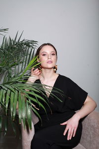 Portrait of young woman standing against wall