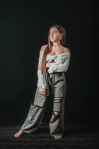 Portrait of smiling young woman against black background