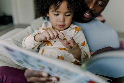 Girl counting number on fingers with father at home