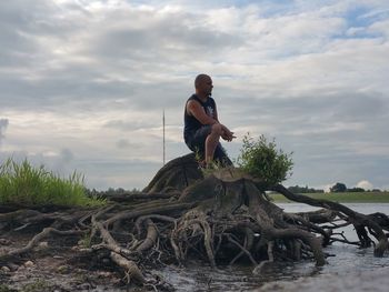 Full length of man on rock at beach against sky