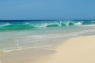 Scenic view of sea waves rushing towards shore against clear sky