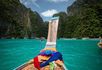 People on boat in sea by mountain against sky