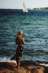 Rear view of young woman standing at beach