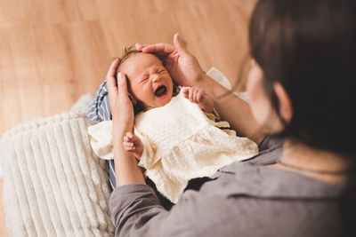 Crying baby girl wake up on mother hands in room closeup. woman with infant girl. motherhood. 