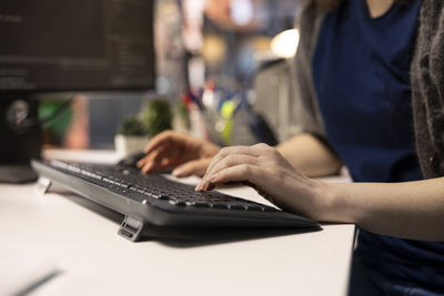 Midsection of woman using laptop on table