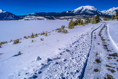 Snow covered road by mountains against sky