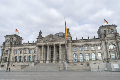 Facade of historical building in city against cloudy sky