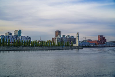 City at waterfront against cloudy sky