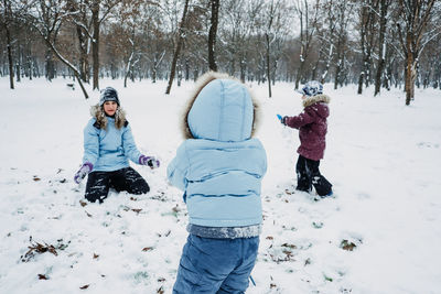 Happy family, friends, mother and kids having fun outdoors in winter snowy nature background. mom
