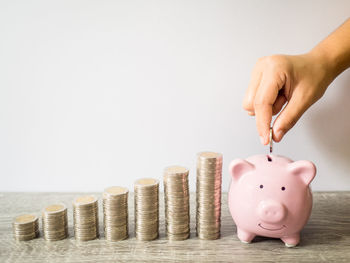 Cropped image of hand holding coin stack against white background