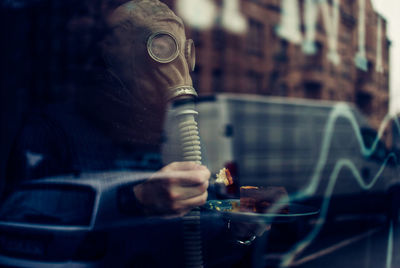 Man wearing gas mask seen through window