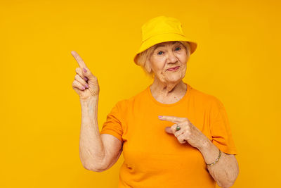 Portrait of smiling young woman gesturing against yellow background